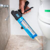 This image displays the OX Pro Rodless Sealant Gun - 400ml 13.5oz Being used on a toilet